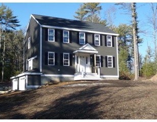 Two-story gray house with white trim and columns on a brown dirt yard, surrounded by trees.