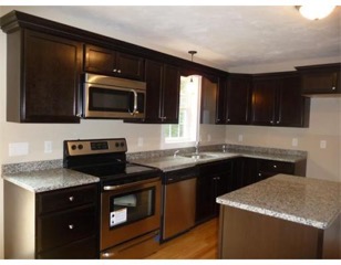 Modern kitchen with dark wood cabinets, stainless steel appliances, and granite counters.