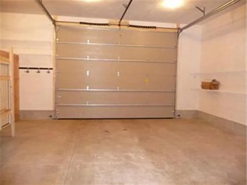 Empty garage with a closed metal door, bare walls, and concrete floor.