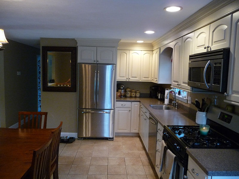 Modern kitchen with white cabinets, stainless steel appliances, and a dining table.