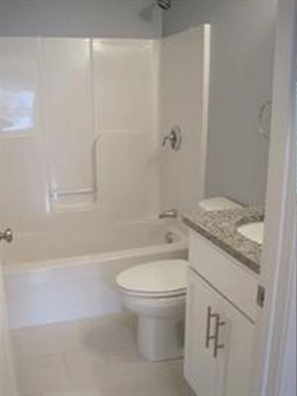 Small bathroom with a white bathtub, toilet, and granite countertop sink.