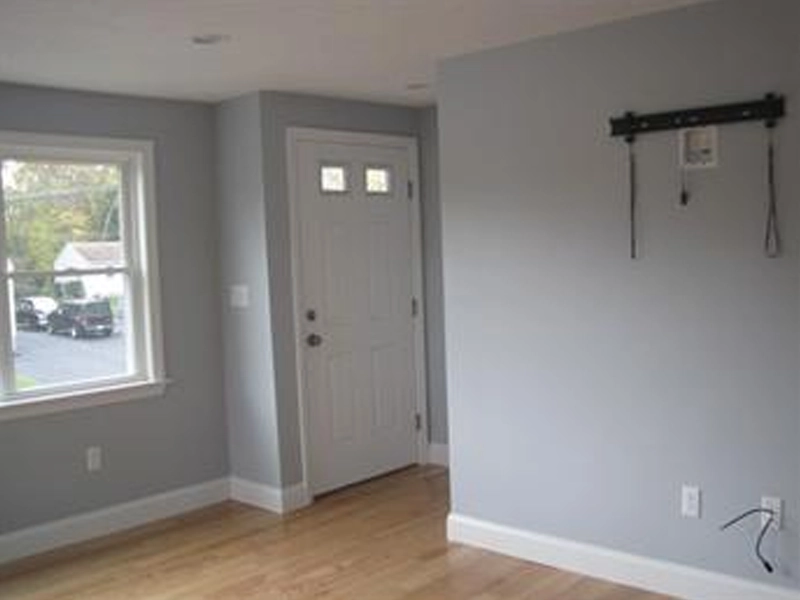 Small entryway with light gray walls, wood floor, and a door next to a window.