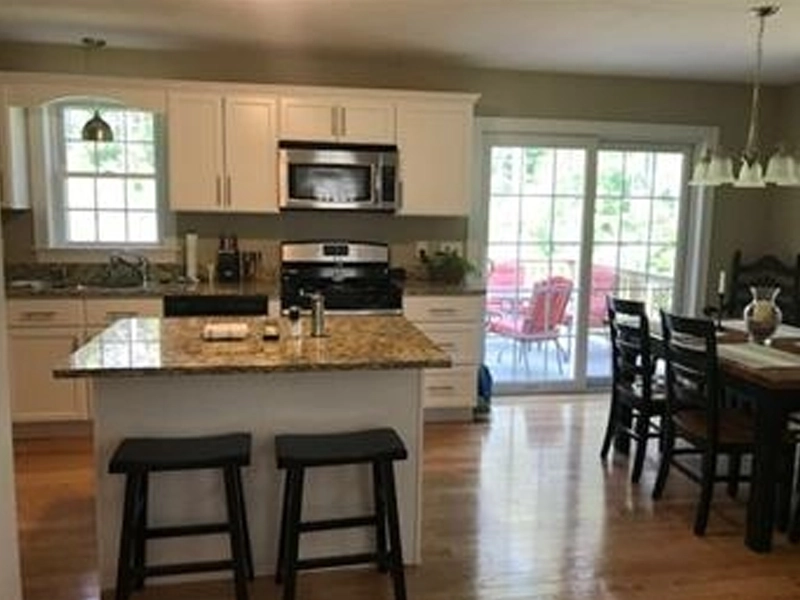 Modern kitchen with island, stools, dining table, and sliding glass doors to a patio.
