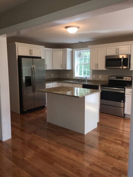 Modern kitchen with white cabinets, stainless steel appliances, and a granite island.