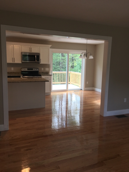 Kitchen and dining area with wooden floors, white cabinets, and sliding glass doors to a deck.