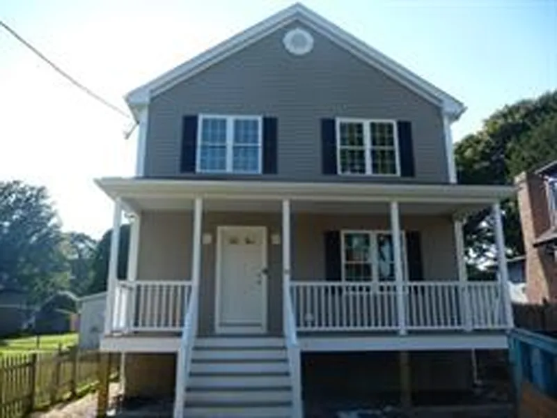 Two-story house with gray siding, white trim, front porch, and black shutters.