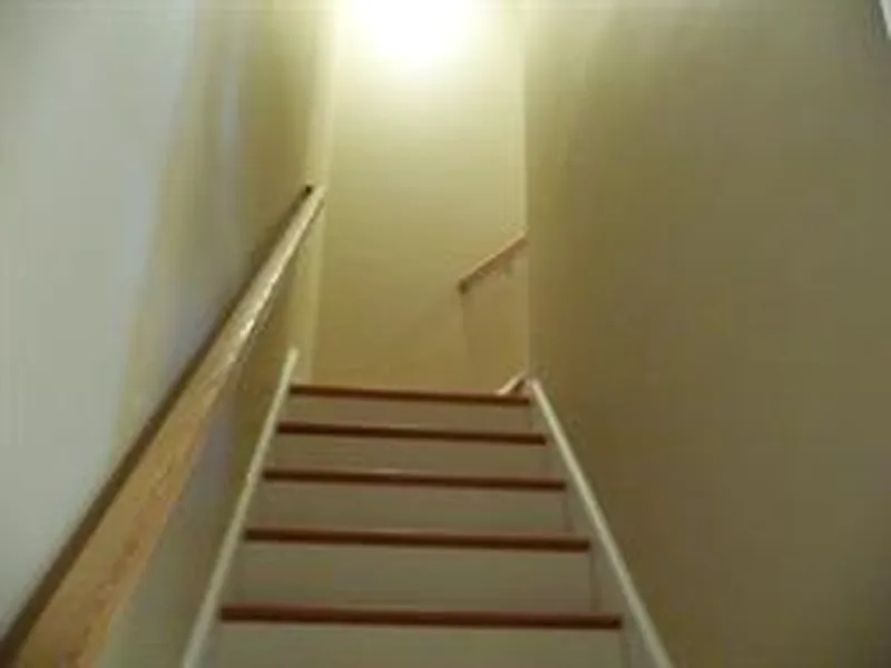 A staircase leading up to a landing, lit by a bright light at the top.