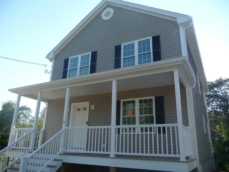 Two-story house with gray siding, white trim, porch, and black shutters on windows.