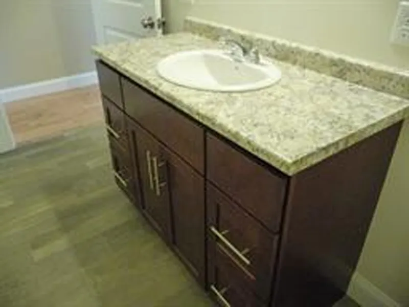 Bathroom vanity with a marble countertop, sink, and dark wood cabinets.