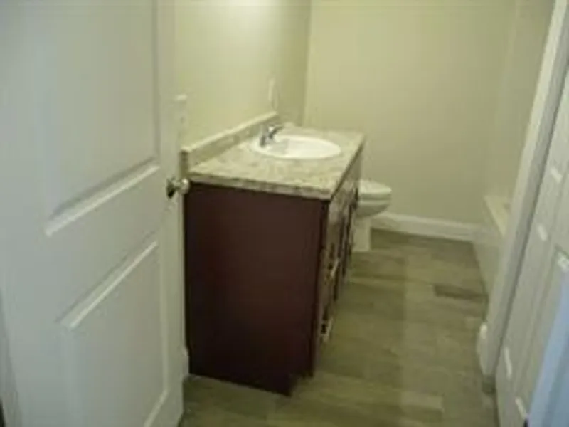 Small bathroom with a sink, countertop, toilet, and beige tile flooring.