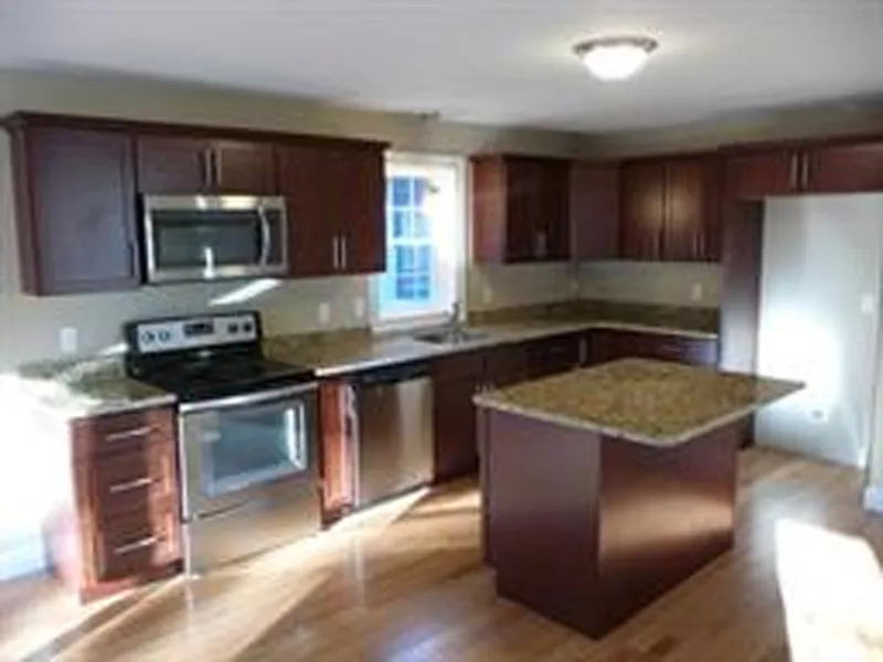 Modern kitchen with dark wood cabinets, stainless steel appliances, and a center island.