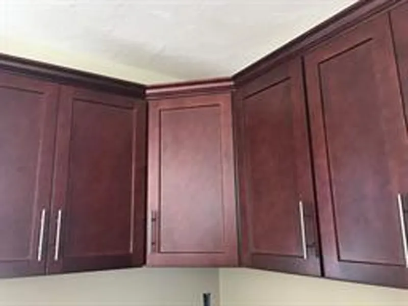 Dark wood kitchen cabinets with a corner cabinet door that cannot be opened fully.