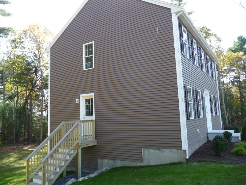 Brown house with white trim, side entrance, and stairs leading up to a small door.