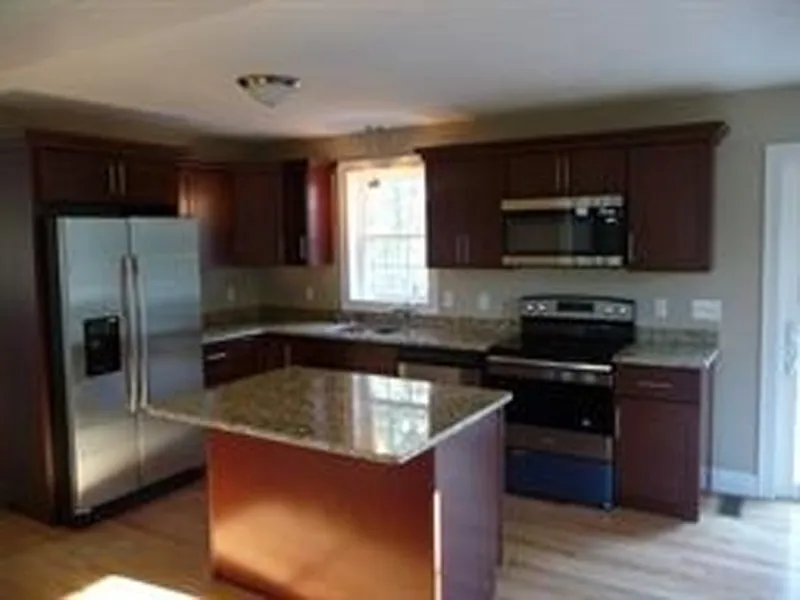 Modern kitchen with dark wood cabinets, granite countertops, and stainless steel appliances.