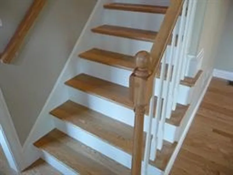 Wooden staircase with white risers and a wooden handrail, leading to an upper floor.