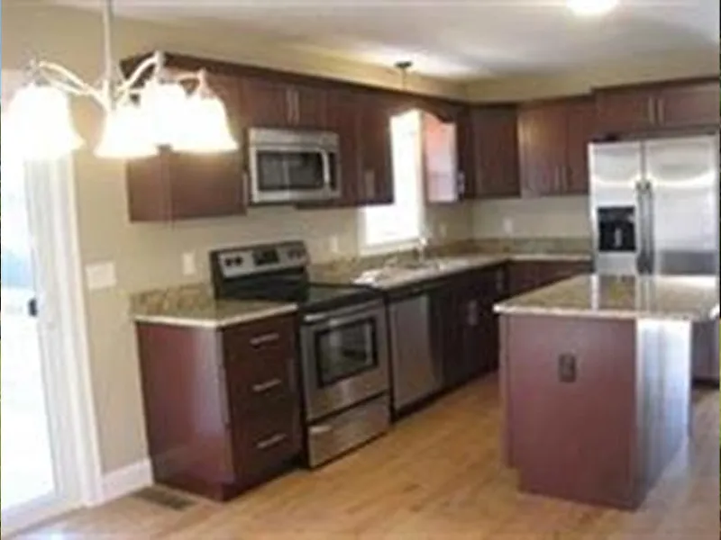 Modern kitchen with stainless steel appliances, dark wood cabinets, and granite countertops.