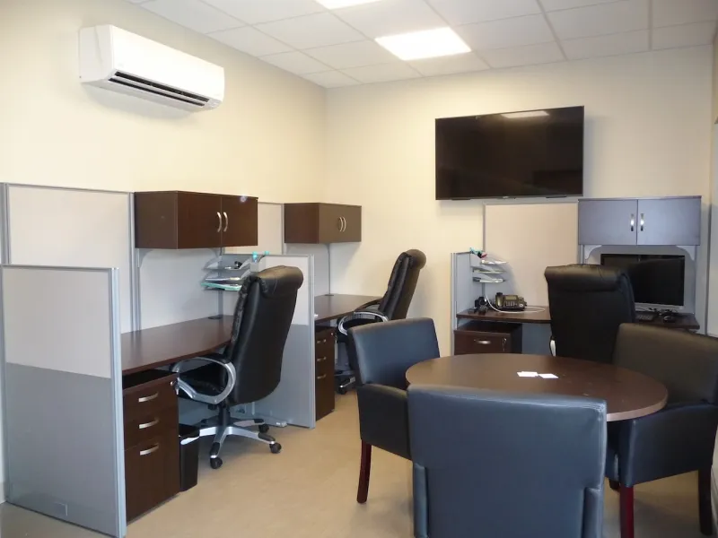 Modern office with desks, computers, black chairs, and a round meeting table.