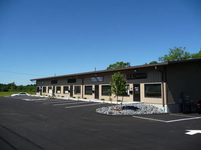 Single-story commercial building with parking lot under a clear blue sky.