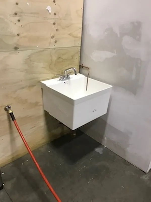 A wall-mounted sink installed in a corner, placed at an unusual angle.