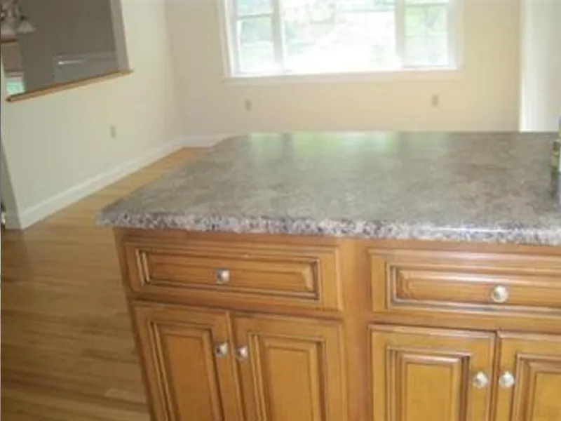 Brown kitchen island with a marble countertop in a bright room with wood floors.