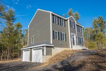 Two-story gray house with white trim and double garage, surrounded by trees.