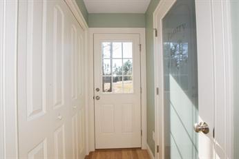A small hallway with a white door, glass panels, and light green walls.