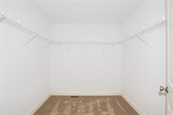 Empty walk-in closet with white walls, carpeted floor, and wire shelving on three sides.
