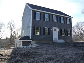 Two-story gray house with white trim, black shutters, and a bare dirt yard.