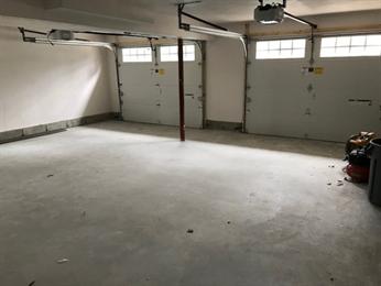 Empty two-car garage with concrete floor, white walls, and closed garage doors.