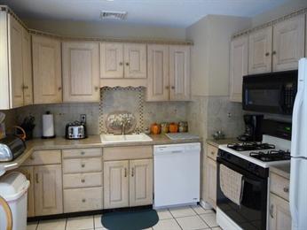 Small kitchen with light wood cabinets, white appliances, and countertop appliances visible.
