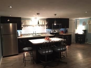 Modern kitchen with dark cabinets, island seating, and stainless steel appliances.