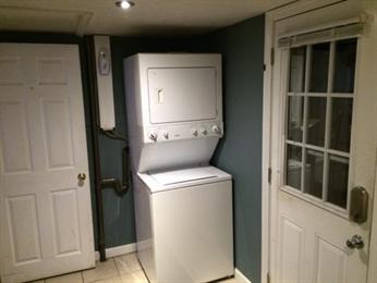 Stacked washer and dryer unit in a small laundry room with two doors.