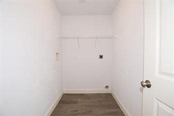 Empty white laundry room with a shelf, hook-ups, tile floor, and an open door.