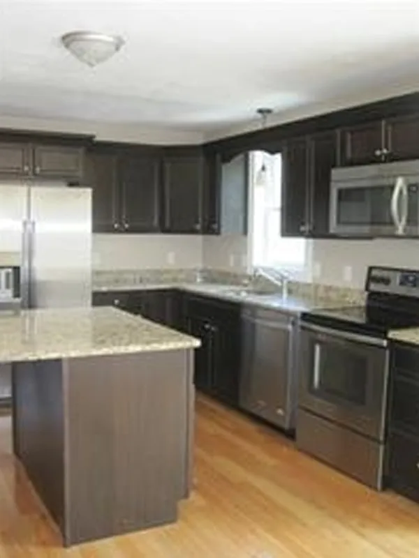 Modern kitchen with dark cabinets, stainless steel appliances, and a granite island.