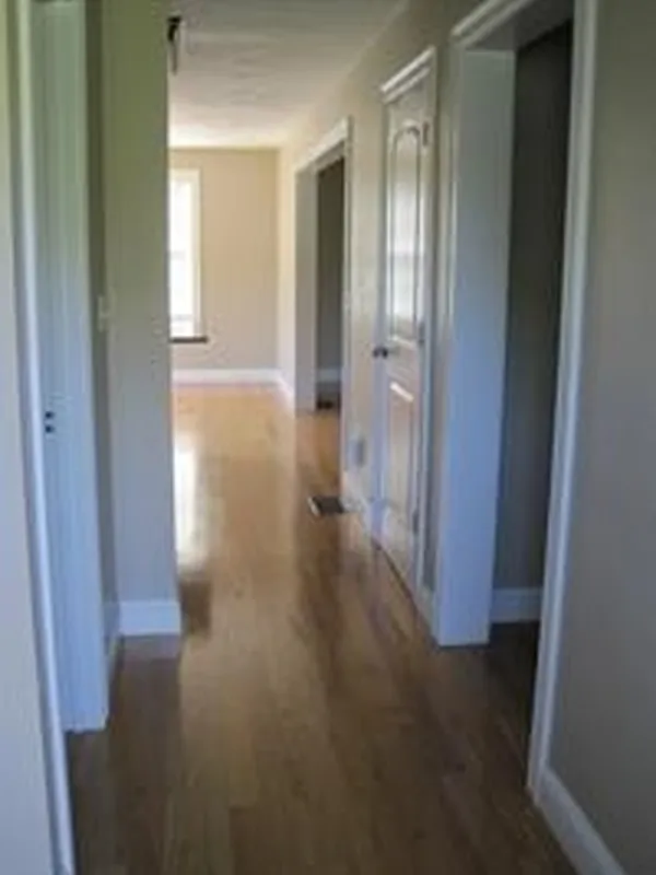 A hallway with wooden floors, beige walls, and white doors leading to other rooms.