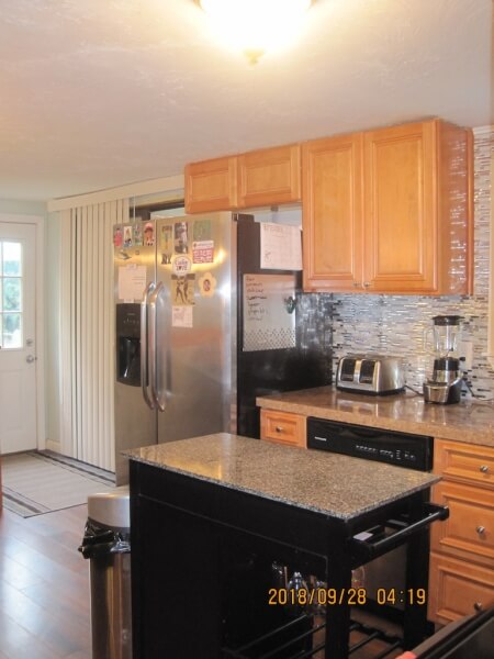 Modern kitchen with wooden cabinets, stainless appliances, and a small island.