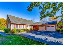 Single-story house with a two-car garage, red shutters, and landscaped front yard.