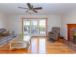 Bright living room with hardwood floor, sofa, recliner, fireplace, and glass doors.