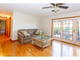 Bright living room with a brown sofa, glass coffee table, and French doors to a patio.