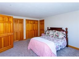 Bedroom with a wooden bed, floral bedding, pink blanket, and wooden closets.