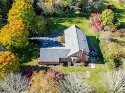 Aerial view of a house surrounded by trees with autumn foliage in a spacious yard.