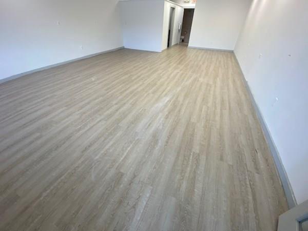 Empty room with light wood flooring, white walls, and an open doorway in the back.