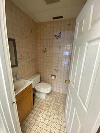 Small bathroom with butterfly-themed tiles, a toilet, sink, and a white door.