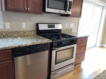Modern kitchen with stainless steel appliances, granite countertops, and wood cabinets.