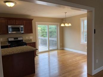 Kitchen with wood cabinets and dining area by sliding glass doors to a balcony.