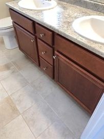 Double bathroom vanity with brown cabinets, granite countertop, and white sinks.