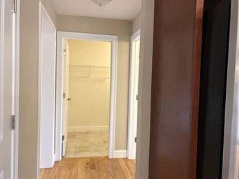 A hallway with wooden floors and three open white doors leading to different rooms.