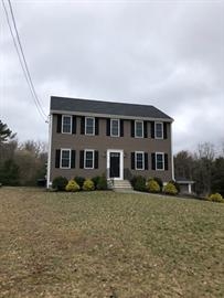 Two-story brown house with black shutters, white trim, and a grassy front yard.