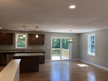 Open kitchen and dining area with wood floors, island, and sliding glass doors to a deck.