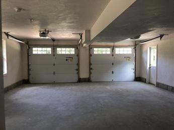 Empty two-car garage with two closed doors, side window, and a door to the right.